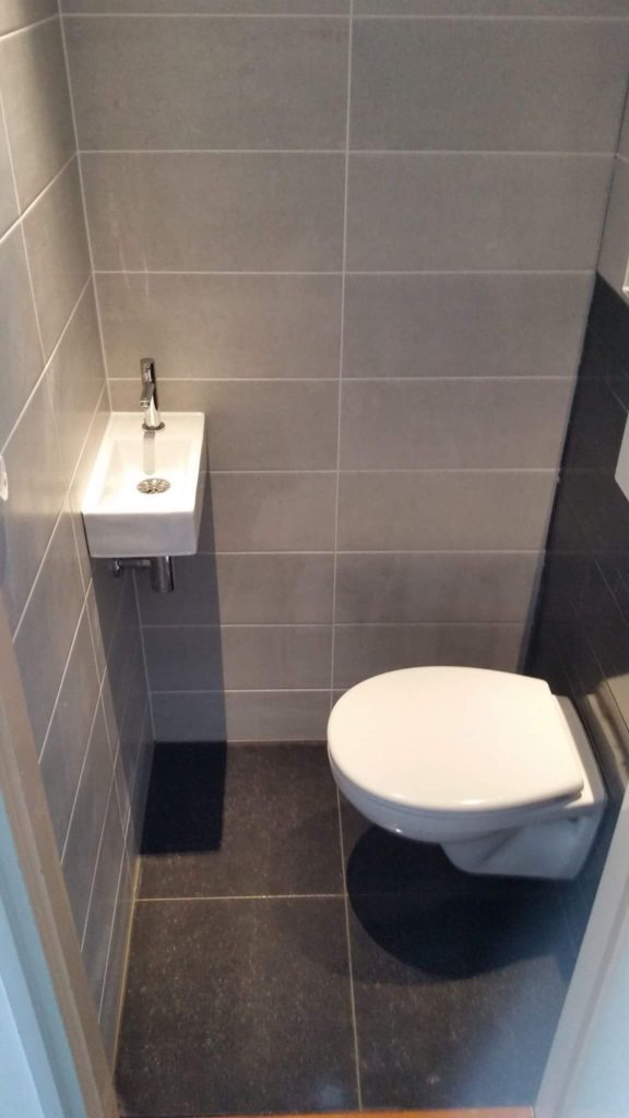 Toilet met zwarte vloertegels en wasbak